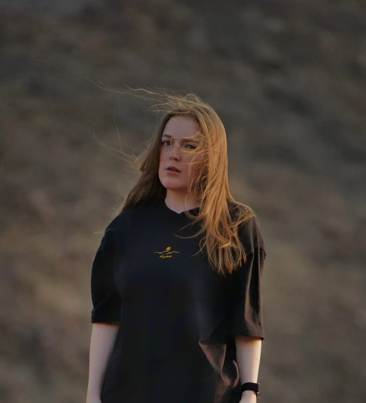 The Al Quaa Galaxy tee worn in the Hajar mountains — the embroidered mark on the chest. Female model wears M in the Oversized fit.