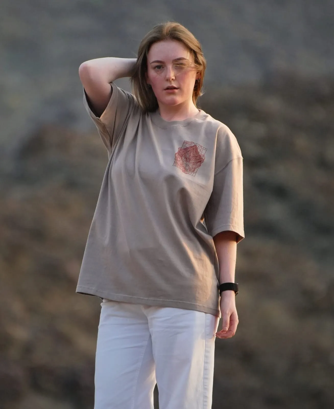 The Hajar Mountains tee worn in the Hajar themselves — the contour-line mountain mark on the chest. Female model wears M in the Oversized fit.