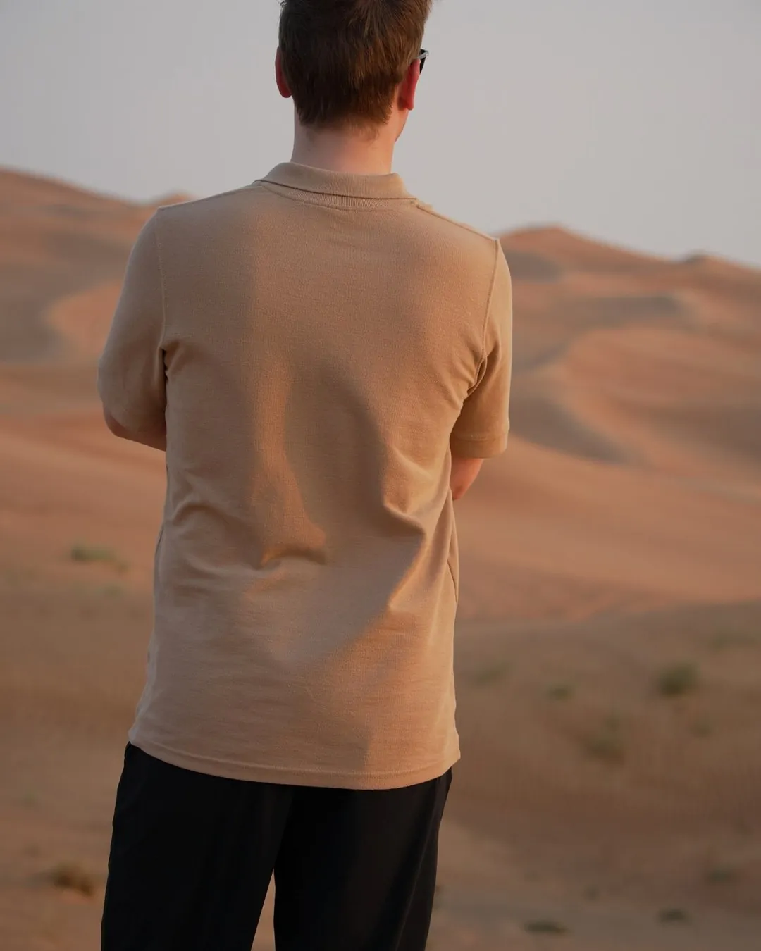 The Sahra Polo held at the hem — the weight of the piqué and the side seam